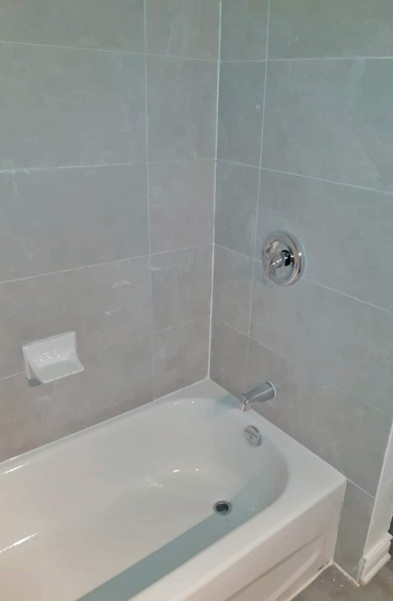 A white bathtub with a silver faucet and a silver shower head.
