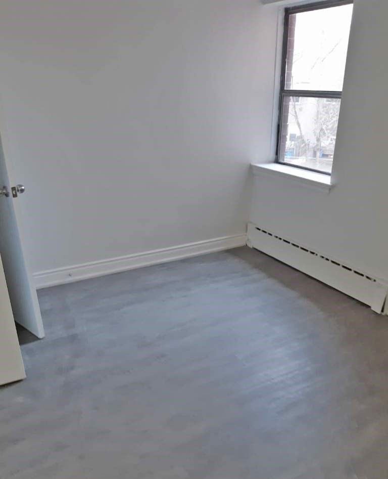 A room with a window and a white wall.