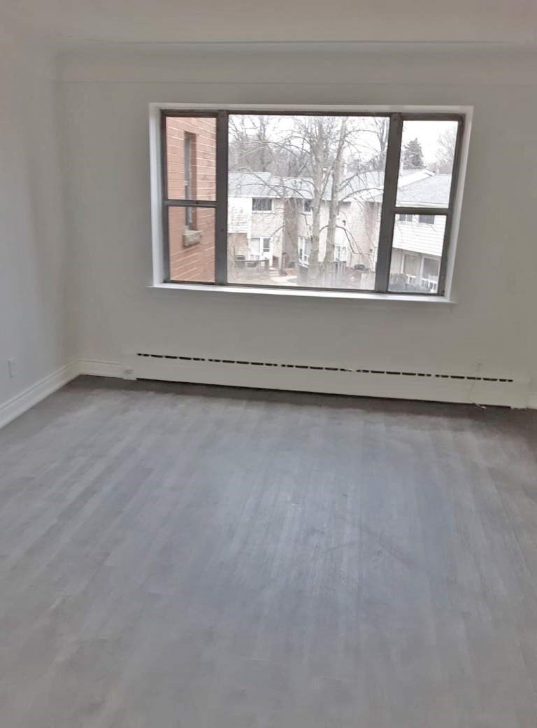 A room with a window and a white wall.