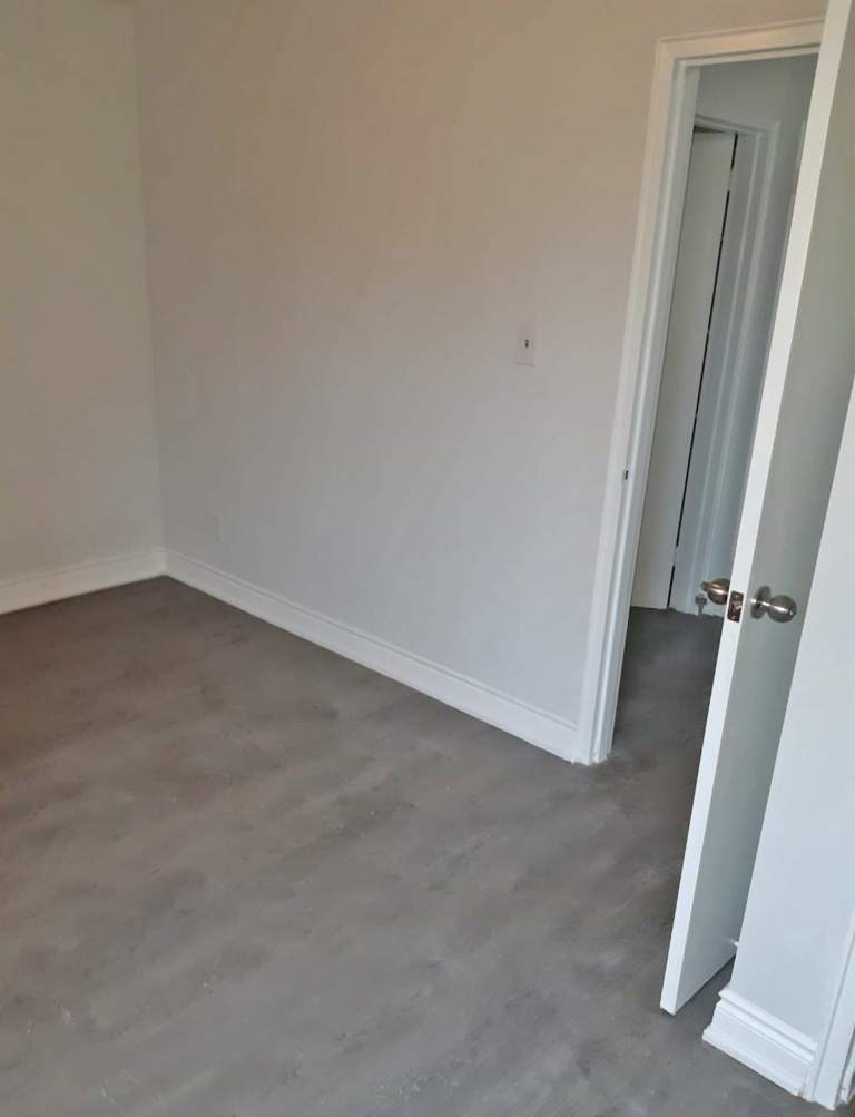 A room with a closed door and a grey floor.