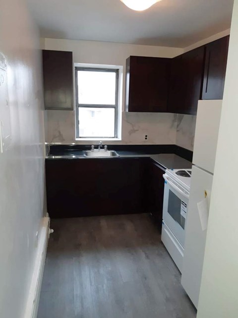 A kitchen with a white fridge and black countertops.