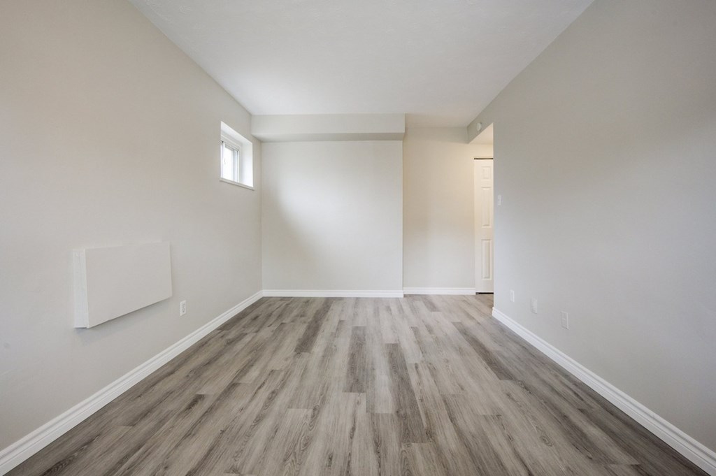 A room with wooden flooring and white walls.