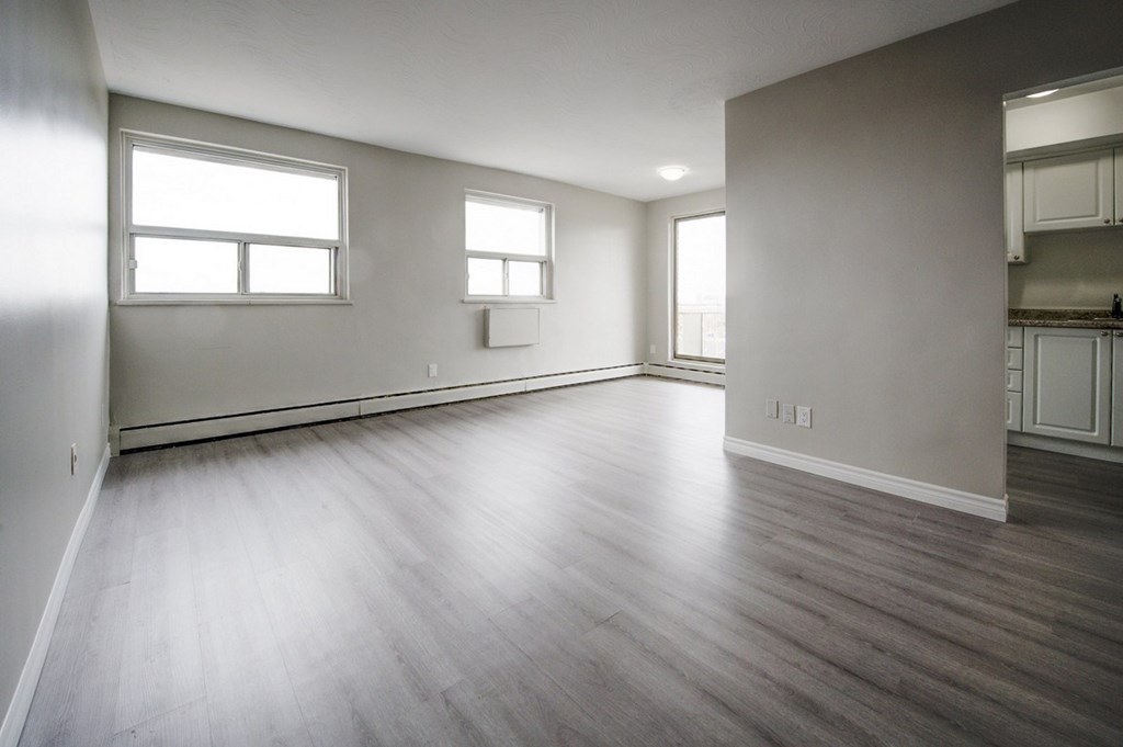 A large empty room with wooden floors and three windows.