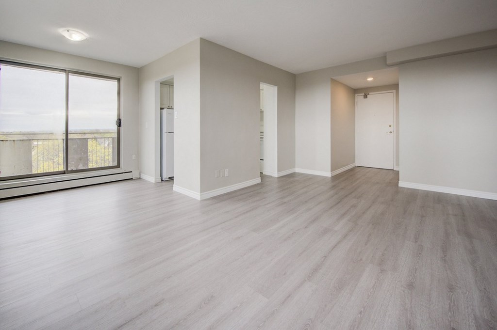 A spacious room with wooden flooring and white walls.