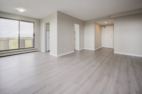 A spacious room with wooden flooring and white walls.