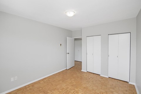 A room with white walls and wooden flooring with three white doors.