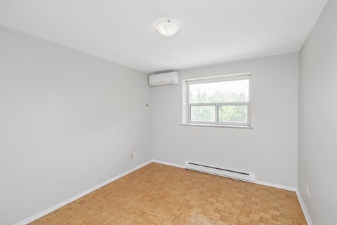 A room with a window and a radiator on the floor.