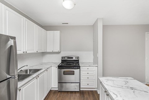 A kitchen with white cabinets and a marble countertop.