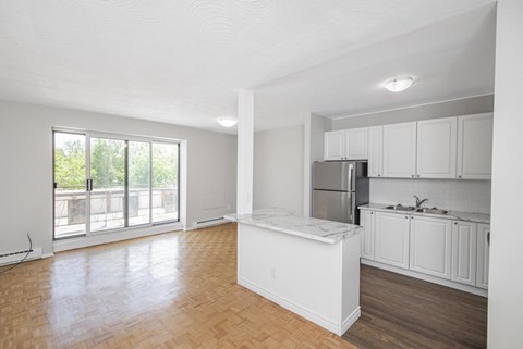 A kitchen with white cabinets and a marble island.