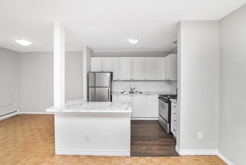 A kitchen with white cabinets and a marble island.