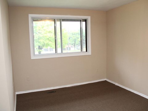 A room with a window and carpeted floor.