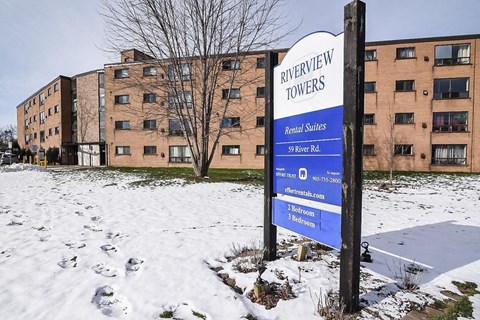 A sign for Riverview Towers stands in front of apartment buildings.