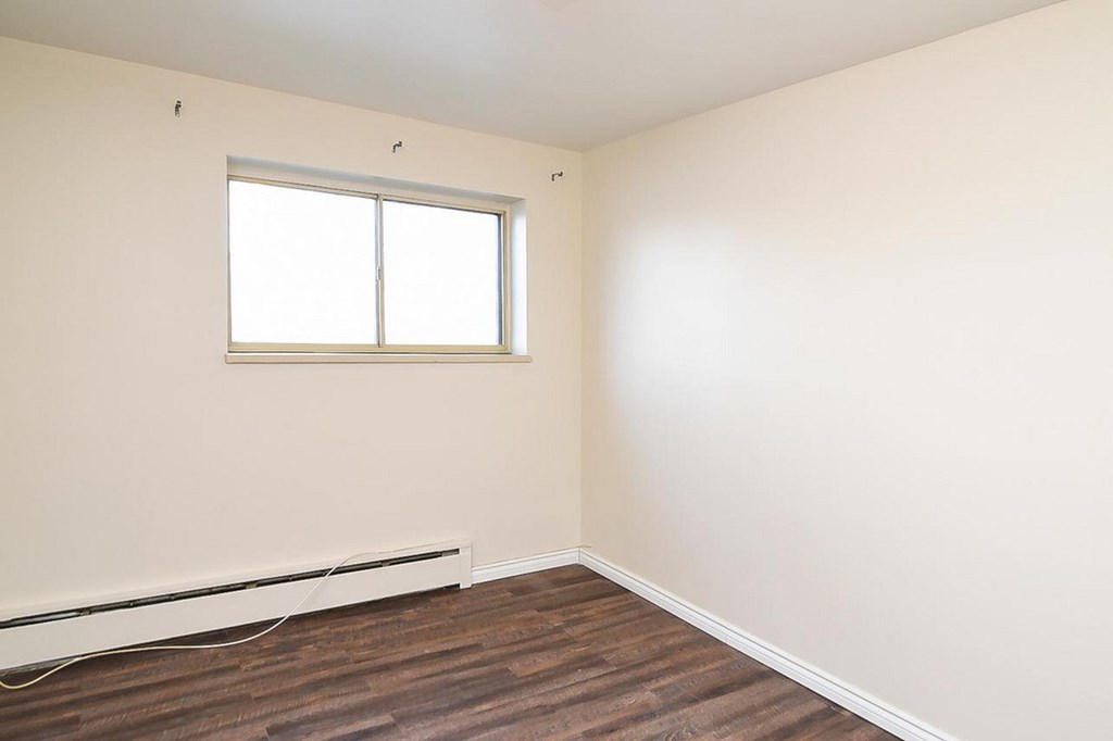 A room with a window and a radiator on the floor.