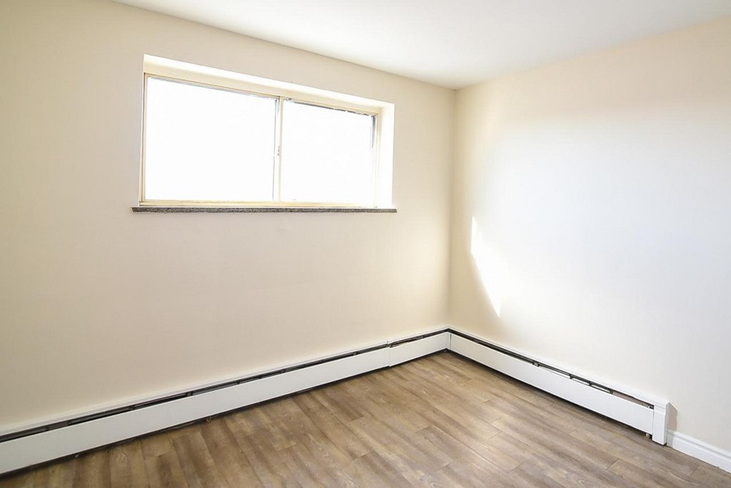 A room with a window and wooden flooring.