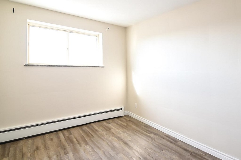 A room with a window and wooden flooring.