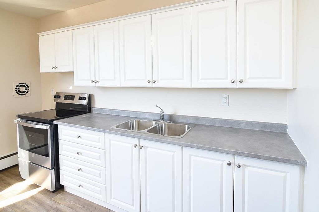 A kitchen with white cabinets and a black oven.