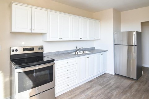 A kitchen with white cabinets and a stainless steel refrigerator.