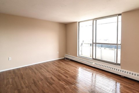 Empty room with wooden floor and large windows.