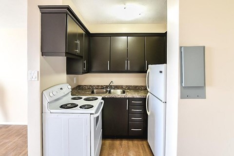 A kitchen with black cabinets and a white refrigerator.