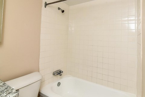 A white bathtub with a shower head and faucet.