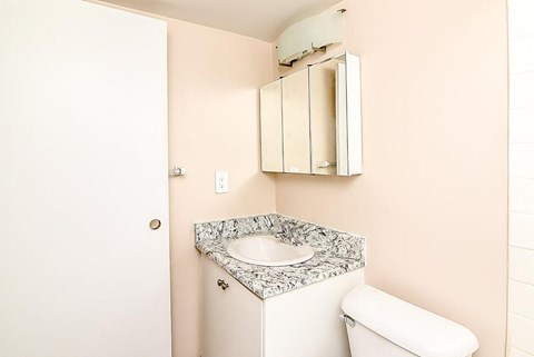A bathroom with a toilet, sink and medicine cabinet.