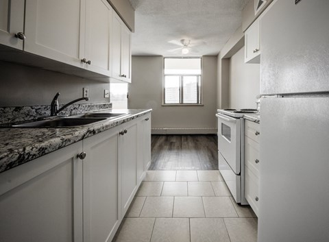 A kitchen with white cabinets and a marble countertop.