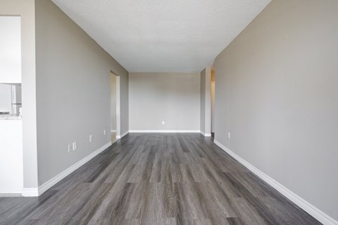 A long, empty hallway with wood flooring and white walls.