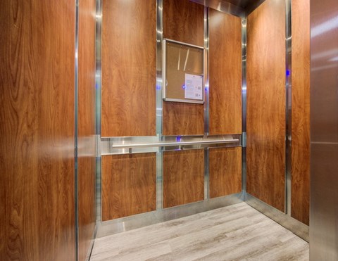 A wooden elevator with a metal frame and a paper on the wall.