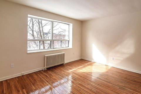 A room with a window and a radiator on the floor.