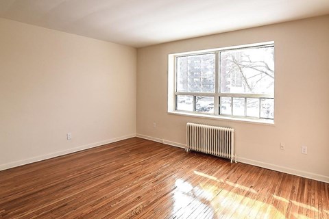 A room with a window and a radiator on the floor.