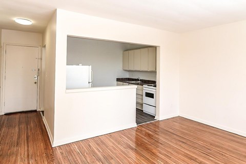 A kitchen with a white countertop and wooden floors.