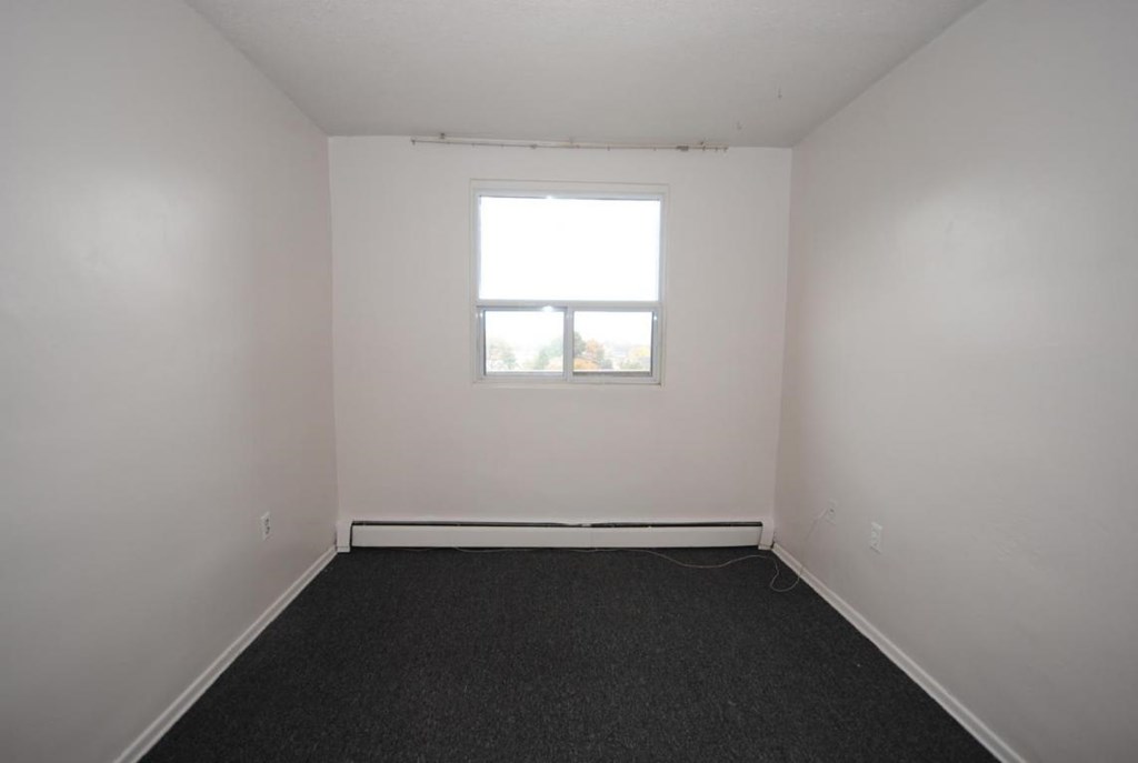 A room with a window and a carpeted floor.