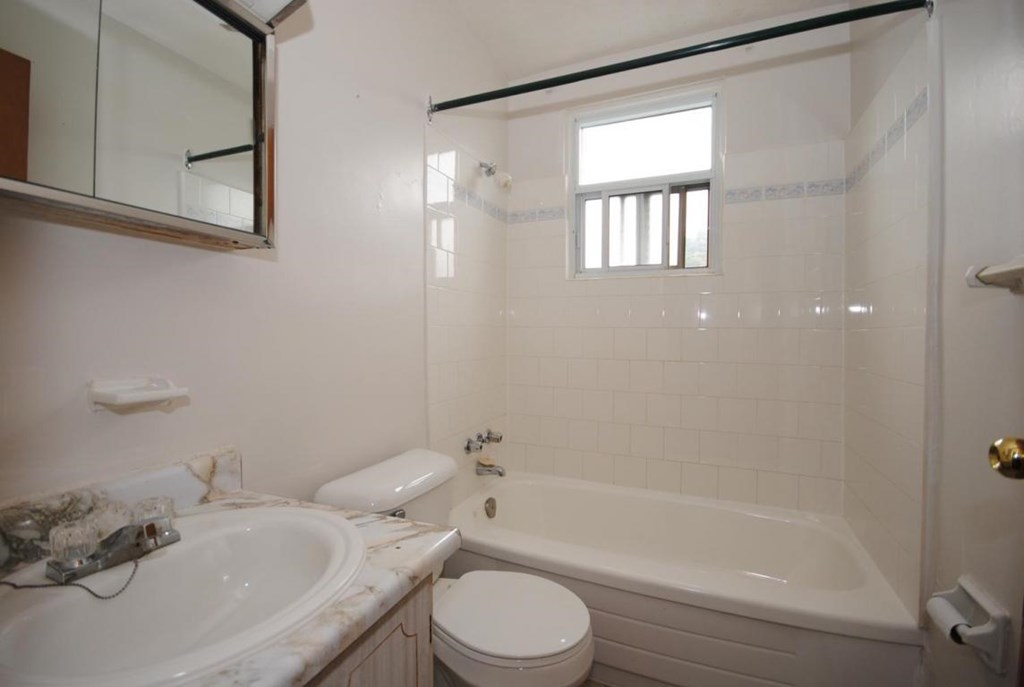 A white bathroom with a tub, toilet, and sink.