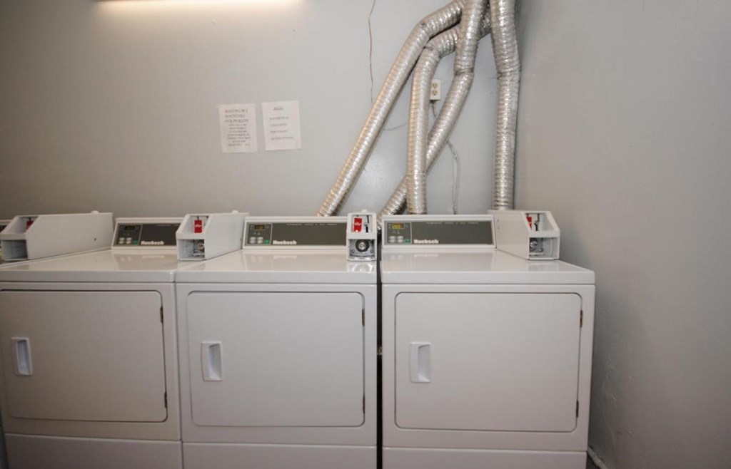 A row of washing machines are lined up against a wall.