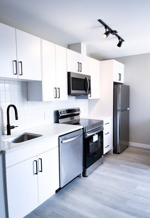 A modern kitchen with white cabinets and stainless steel appliances.