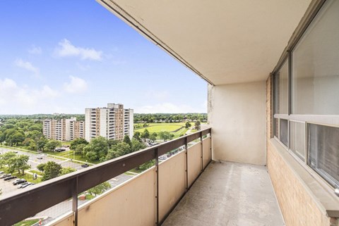 A balcony with a view of a parking lot and buildings.