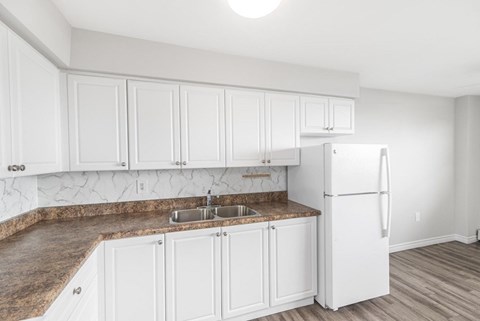 A kitchen with white cabinets and a granite countertop.
