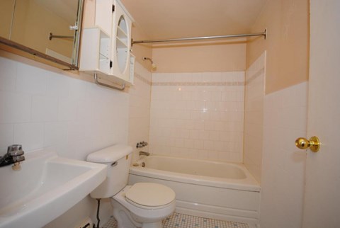A white toilet sits in a bathroom next to a bathtub and sink.
