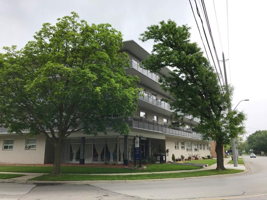 A tree in front of a building with a balcony.
