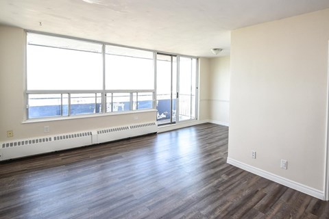 A large empty room with wooden floors and a view of the outside through the windows.