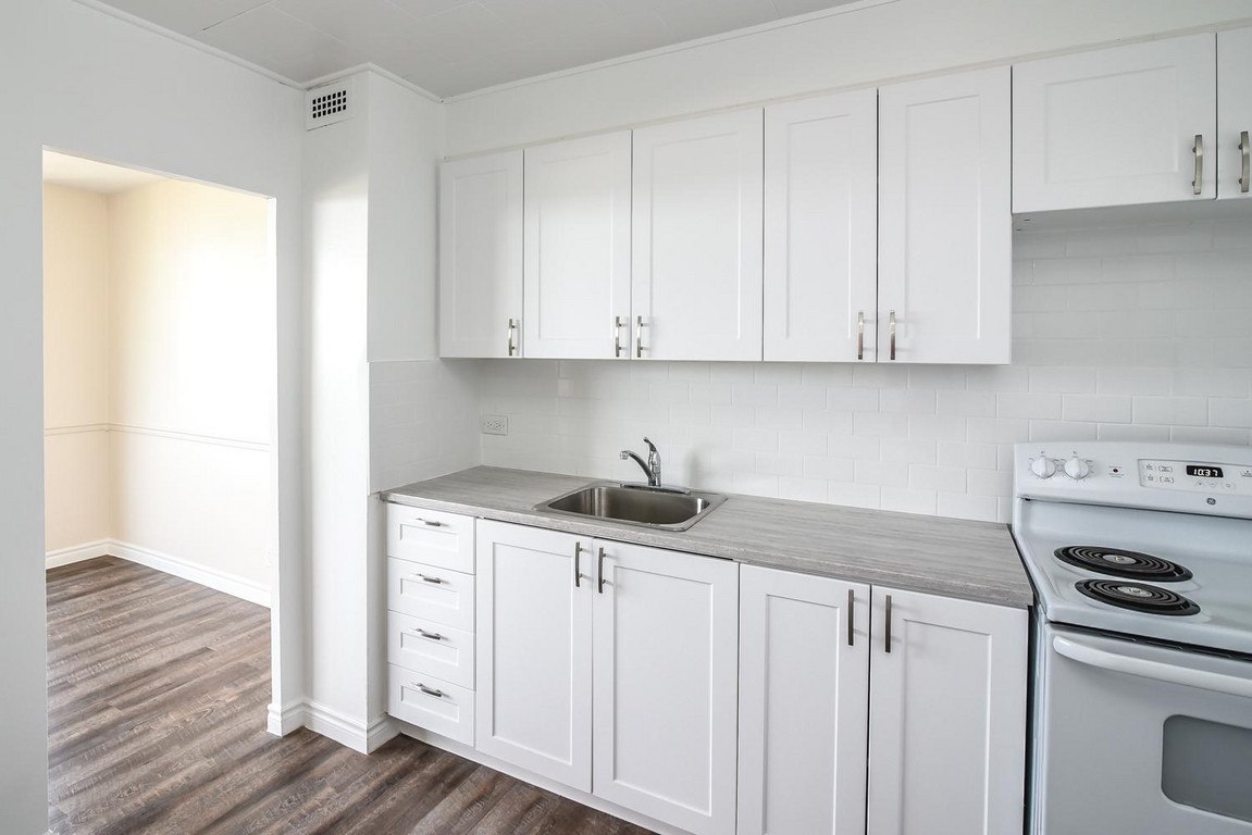 A kitchen with white cabinets and a stove top oven.