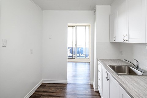 A kitchen with white cabinets and a wooden floor.