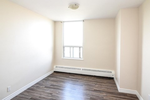 A room with a window and a radiator on the floor.