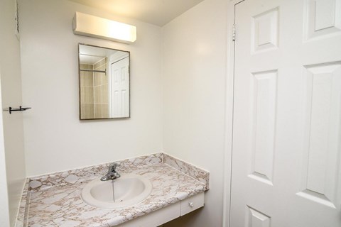 A white bathroom with a sink and mirror.