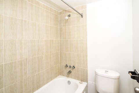 A white toilet sits next to a bathtub in a bathroom.