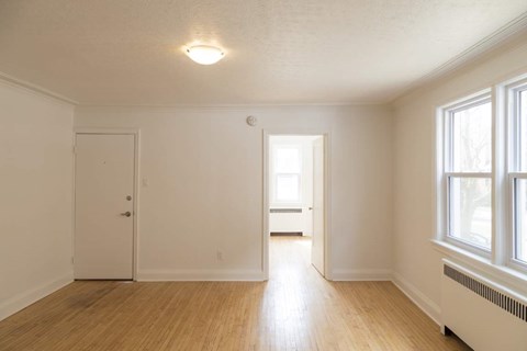 A room with a white door, a window, and a wooden floor.