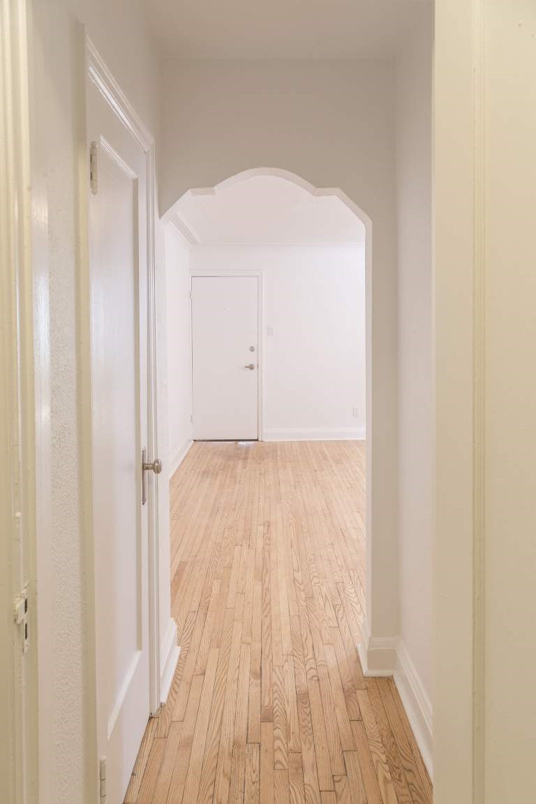 A hallway with a wooden floor and white walls.