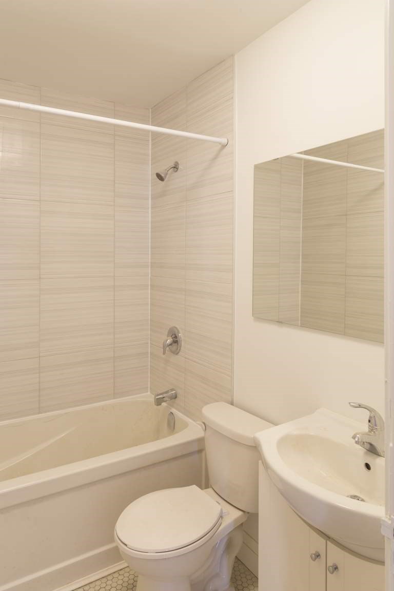 A white toilet sits next to a white sink in a bathroom.