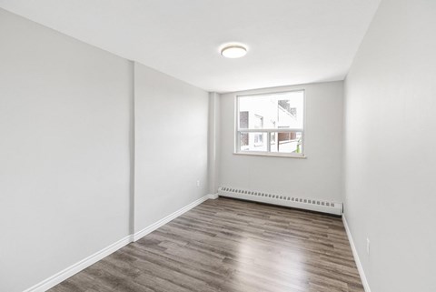 A room with a window and a view of buildings outside.