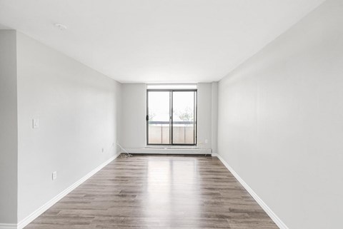 A large empty room with wooden floors and a window.